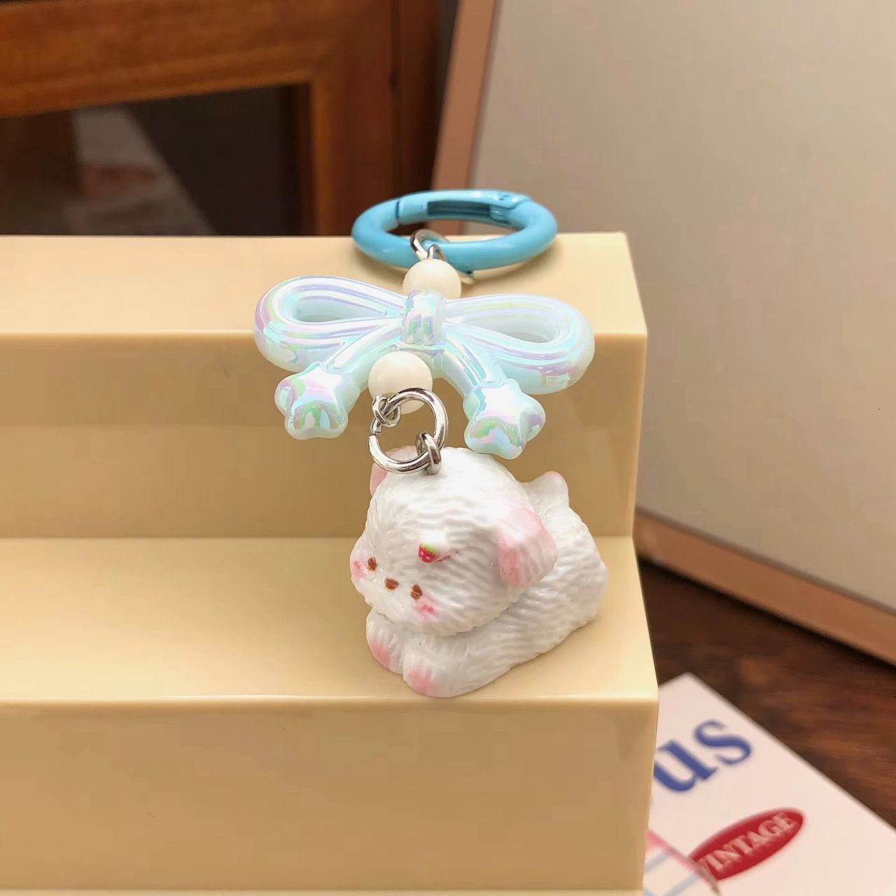 Pastel blue aesthetic keychain featuring a pearlescent ribbon bow and a cute white puppy figurine with pink accents.