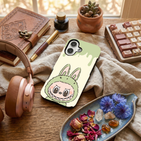 Glossy phone case featuring a cute mint green Labubu monster character in a bunny suit, resting on an aesthetic wooden desk setup.