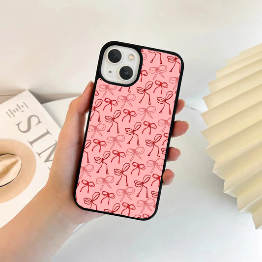 Phone case with a light pink background and an all-over pattern of red hand-drawn sketched ribbon bows.