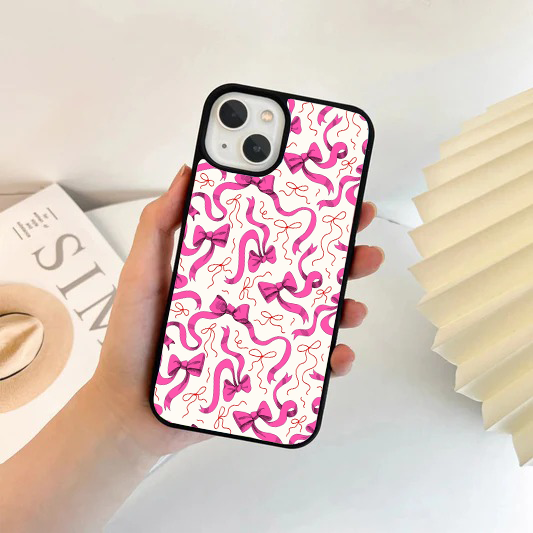 White phone case featuring an all-over pattern of bright magenta flowing ribbons and bows.