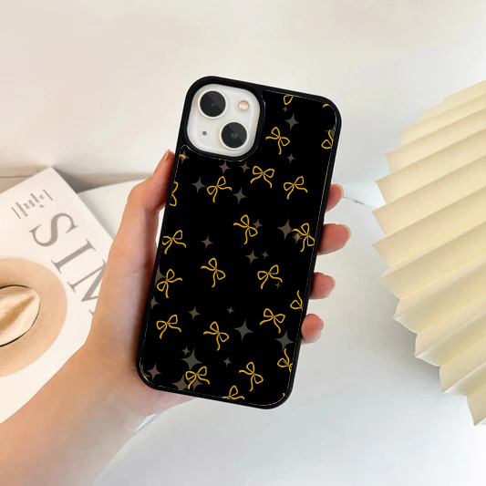 Black phone case with a pattern of delicate, minimalist golden yellow string bows and subtle translucent sparkles.