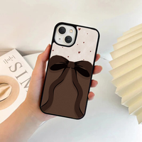 Phone case split horizontally; the top is cream with tiny red hearts, and the bottom features a large, dark brown flowing bow over a solid brown background.