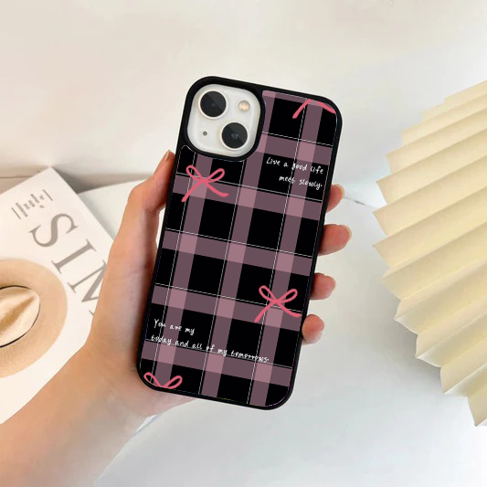Phone case featuring a dark grey and mauve plaid pattern, scattered simple pink bows, and aesthetic white text quotes.