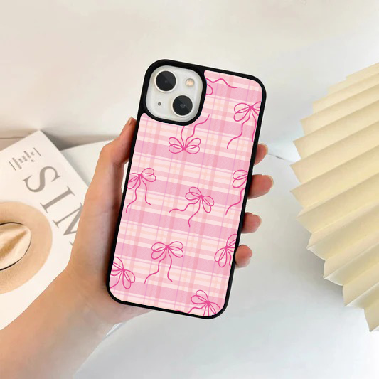 Phone case with a light pink and white gingham plaid background, covered in a pattern of hot pink sketch-style bows.