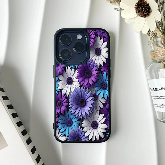 Phone case covered edge-to-edge in a vibrant, realistic 3D-style pattern of purple, bright blue, and white gerbera daisies.
