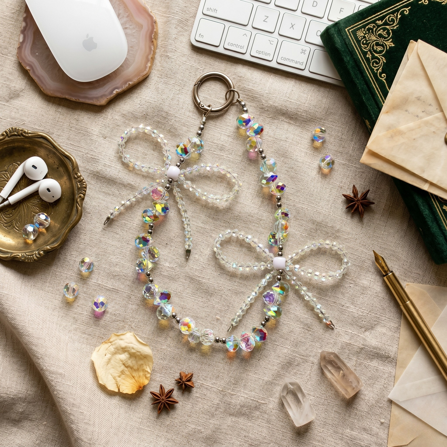 ntricate phone charm made of iridescent clear faceted beads shaped into two large cascading bows, styled on a desk with vintage elements.