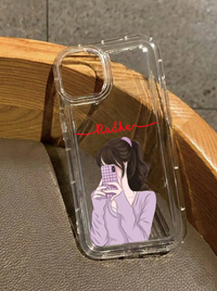 Clear iPhone 16 case showing an illustrated girl in a lavender sweater taking a mirror selfie, personalized with the name Radha in red cursive text.