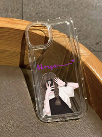 Clear iPhone 16 case featuring an illustration of a girl with braided hair in black overalls taking a selfie, customized with the name Shreya in purple text.